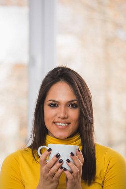 Sarı Jumper bir fincan çay veya kahve tutan gülümseyen kadın