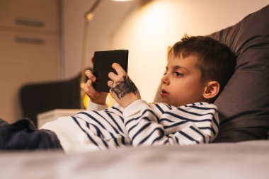 Evde tablet kullanarak mutlu çocuk yatakta yatıyordu