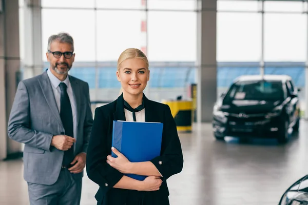 saleswoman and sales man in car dealership showroom