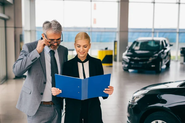 Saleswoman Showing Man Brochure Car Dealership Showroom — Stock Photo, Image