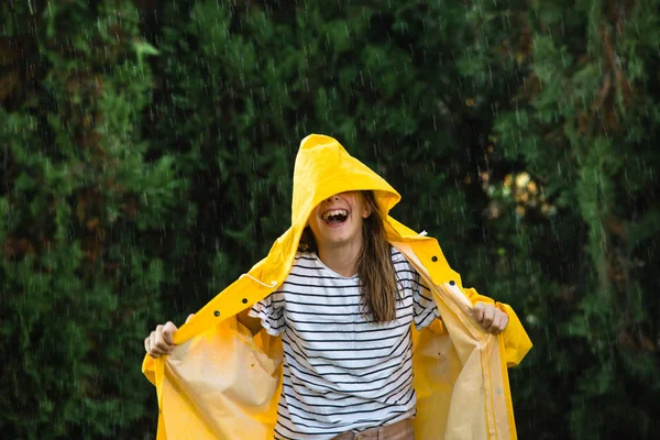 雨の中で遊んで黄色いレインコートで覆われた幸せな女の子 — ストック写真