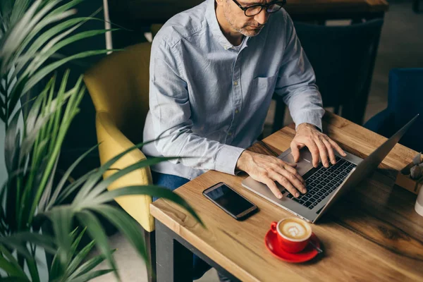 Restoranda kahve molası üzerinde laptop kullanarak adam üst görünümü