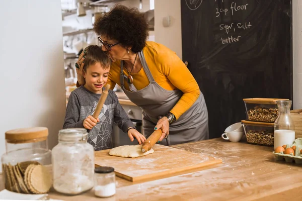 grandson and grandmother cooking together in home kitchen