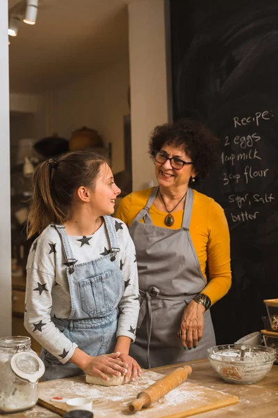 granddaughter and grandmother cooking together in home kitchen