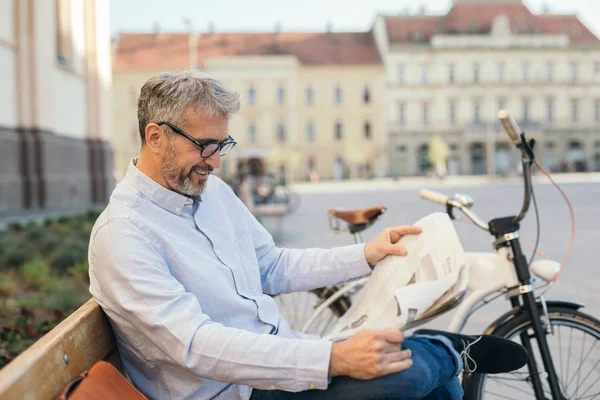 Mature man reading newspaper outdoor in city