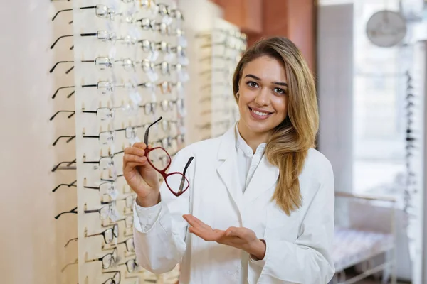 Optik mağazada gözlükleri gösteren optisyen