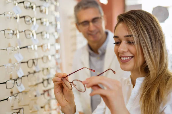 En iyi gözlükleri seçen kadın. Arka planda gözlükçü