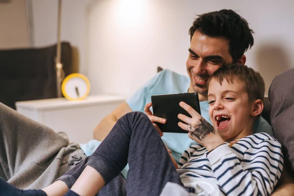 baba ve oğlu evde tablet üzerinde oyun oynuyor