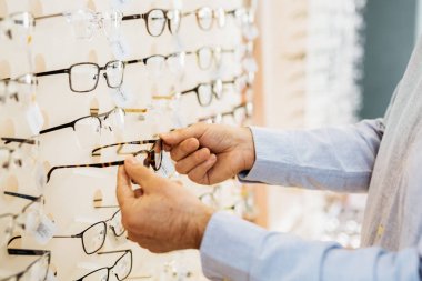 Optik mağaza, ellerin detay gözlük seçme adam closeup.