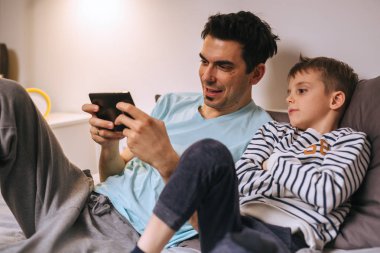 baba ve oğlu evde tablet üzerinde oyun oynuyor