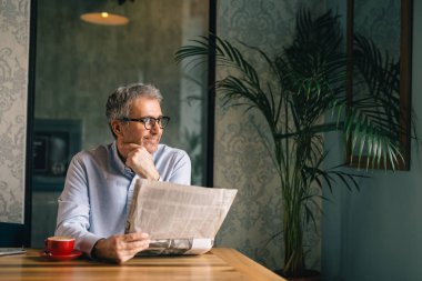 Başarılı gri saçlı adam kafeteryada kahve molası gazete okuma