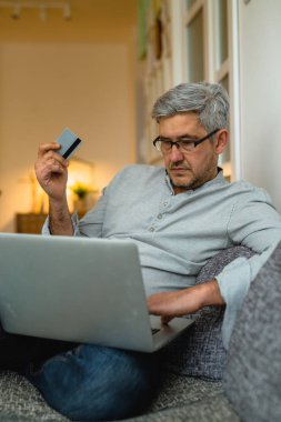 Laptop ve kredi kartı kullanarak evden online gri saç adam alışveriş