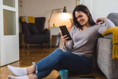genç gülümseyen kadın evde tablet kullanma