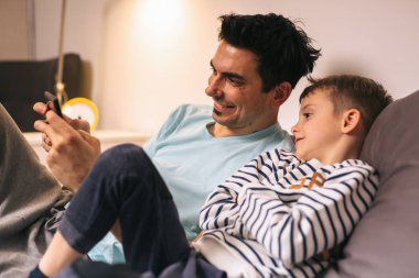 baba ve oğlu evde tablet üzerinde oyun oynuyor