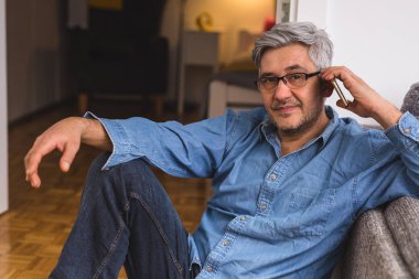 Evde Smartphone kullanarak gri saçlı adam