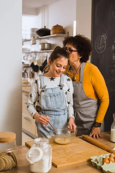 granddaughter and grandmother cooking together in home kitchen