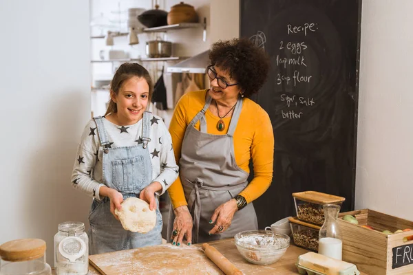 granddaughter and grandmother cooking together in home kitchen