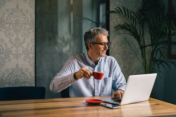 Człowiek Siedzi Przy Stole Kawiarni Przy Użyciu Laptopa Picie Kawy — Zdjęcie stockowe