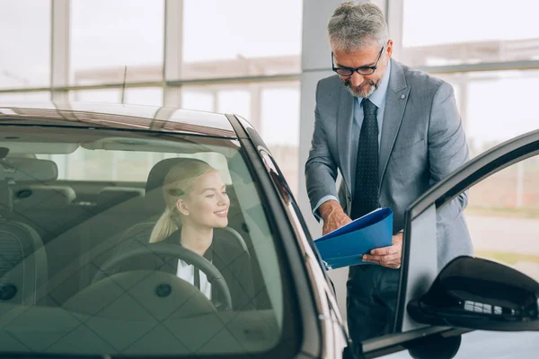 Salesman Showing Woman Brochure Car Dealership Showroom — Stock Photo, Image