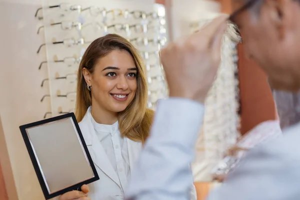 optician helping customer to find best glasses that suits him