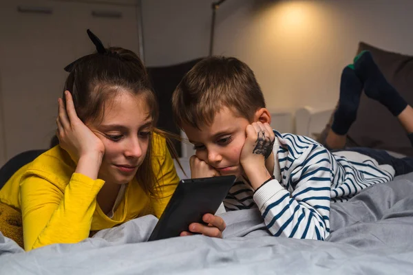 Kinder legen Bett und sehen Cartoons auf ihrem digitalen Tablet — Stockfoto
