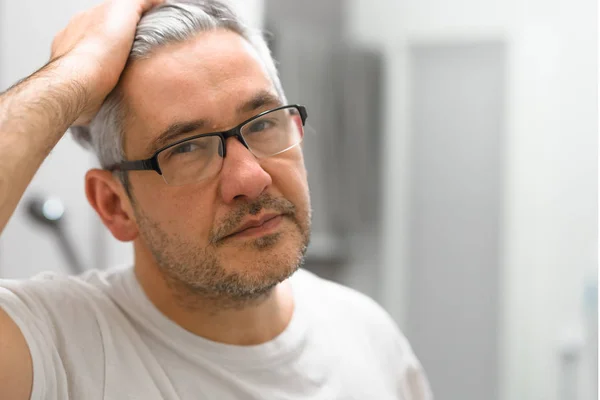 Middle aged man making hair in bathroom