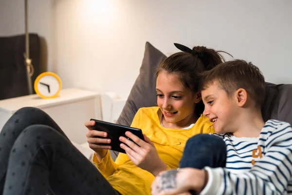 Bruder und Schwester zu Hause in ihr digitales Tablet vertieft — Stockfoto