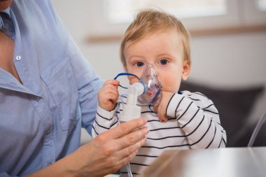 Küçük çocuk nebulizör soluyor.
