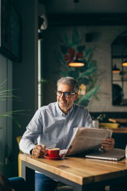 Başarılı gri saçlı adam kafeteryada kahve molası gazete okuma
