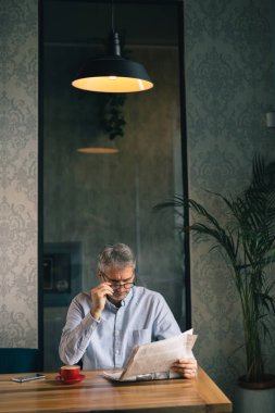 Kafeterya olgun şık adam okuma gazete ve içme kahvesi