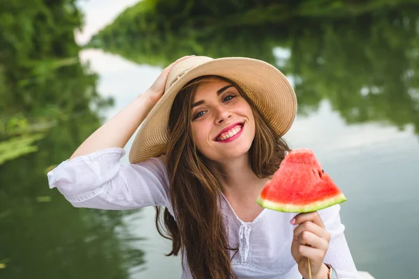 Piękna kobieta jedzenia arbuza na zewnątrz nad rzeką — Zdjęcie stockowe