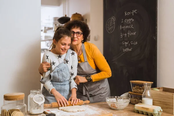 granddaughter and grandmother cooking together in home kitchen