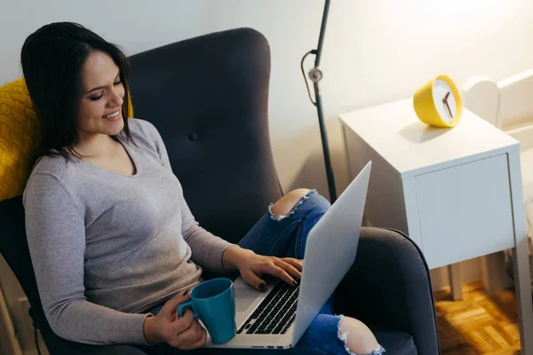 放松的女人使用笔记本电脑和喝咖啡在家里 — 图库照片