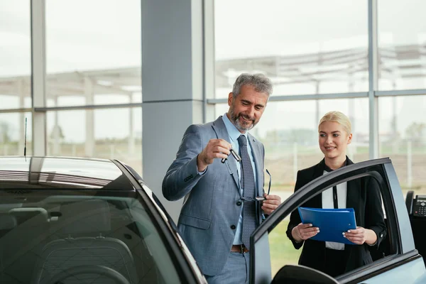 car sell agent with client in car showroom