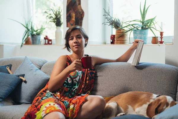 Donna Rilassata Sul Divano Con Libro Lettura Cane Bere Caffè — Foto Stock