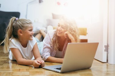 Ana Ana kızı evde dizüstü bilgisayar kullanıyor.