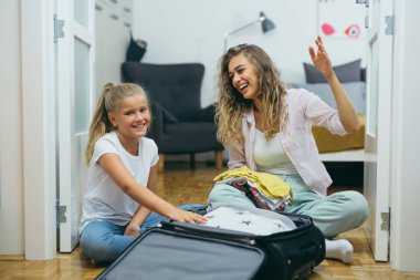 Anne ve kızı tatil için bavullarını hazırlarken eğleniyorlar.