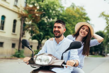 Dışarıda motosikletle gezen mutlu genç çift. Parlak güneş ışığı.