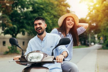Dışarıda motosikletle gezen mutlu genç çift. Parlak güneş ışığı.