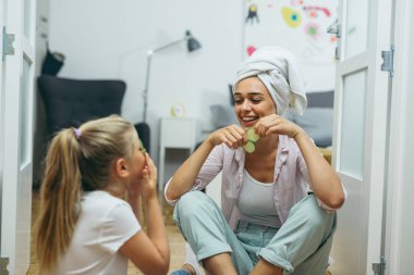 Anne ve kızı evde salatalıklarla cilt bakımı yaparak harika vakit geçiriyorlar.