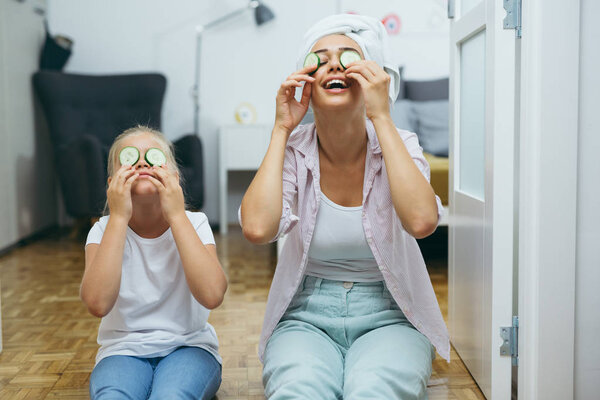 Мать и дочь надевают огурцы на лица дома

