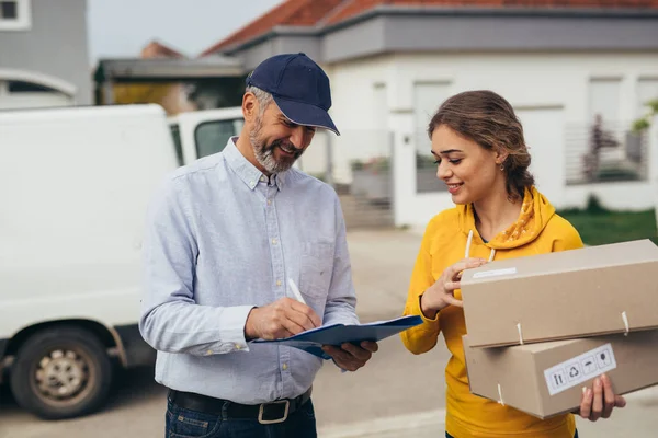 Kadın posta kuryesinden paket kutusu alıyor.