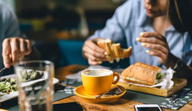 yakın çekim kahve fincanı. İnsanlar arka planda bulanık yemek yiyor