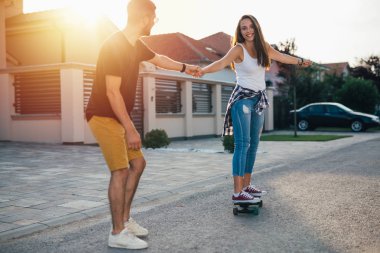 Romantik mutlu çift açık havada kaykay kullanıyor.