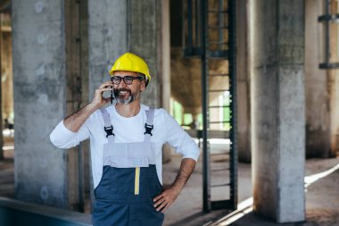 İnşaat işçisi yerinde akıllı telefon kullanıyor.