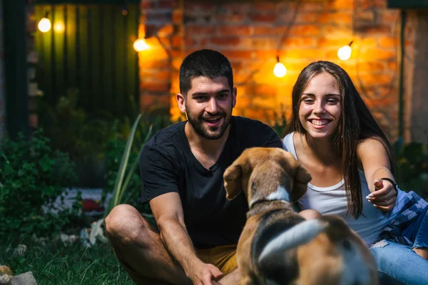 Erkek ve kadın dışarıda köpekle oynuyorlar.
