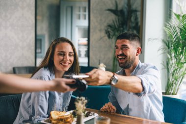 Adam lokantada akıllı telefonla faturayı ödüyor.