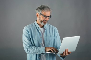 Orta yaşlı bir adamın bilgisayar kullanırken çekilmiş bir fotoğrafı.