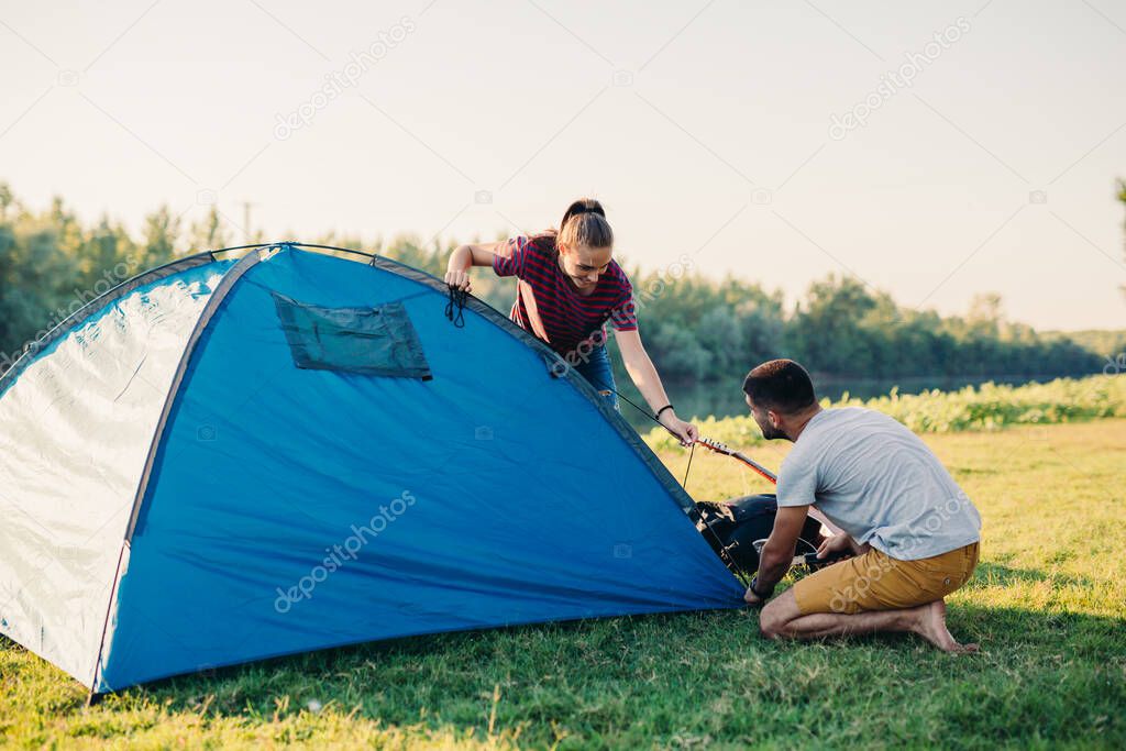 friends preparing tent for camping outdoor