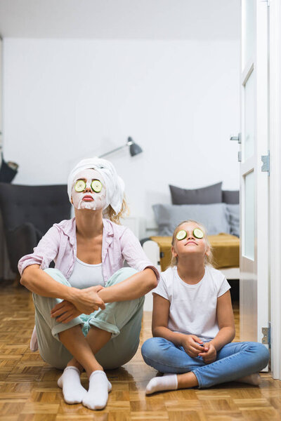 мать и дочь надевают косметическую маску для лица дома